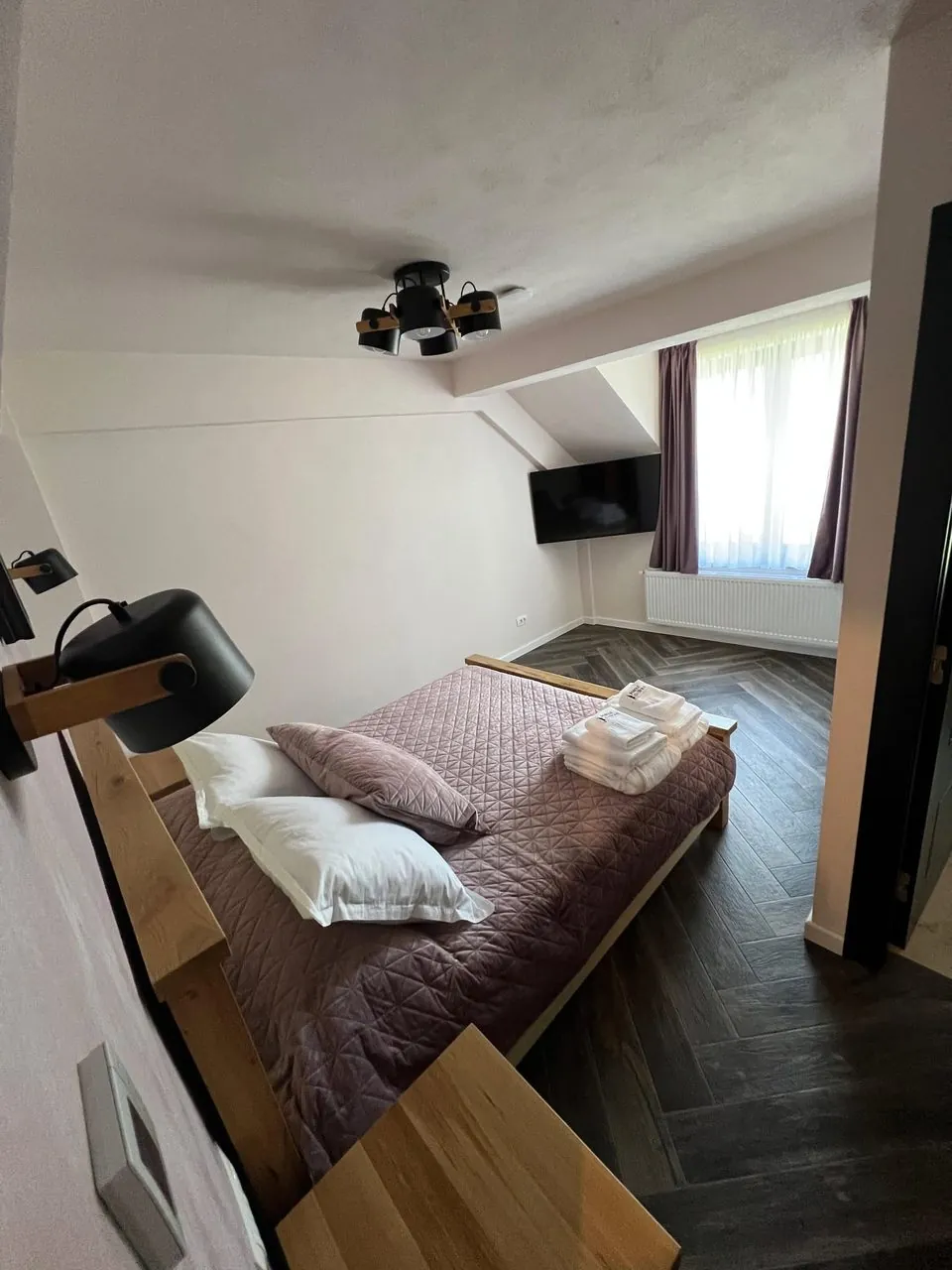Dormitor cu lenjerie gri și pardoseală din lemn