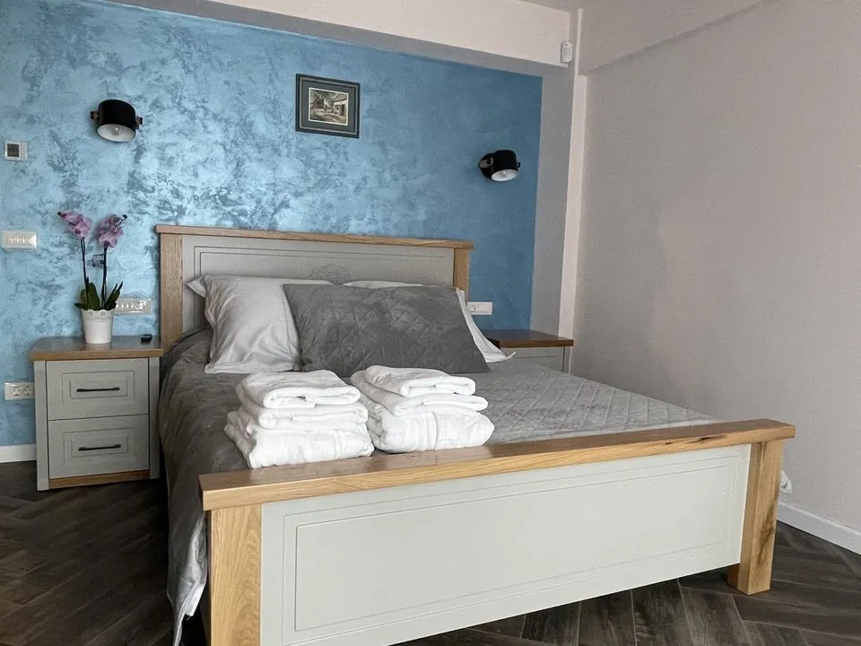 Dormitor cu perete albastru și pat matrimonial din lemn
