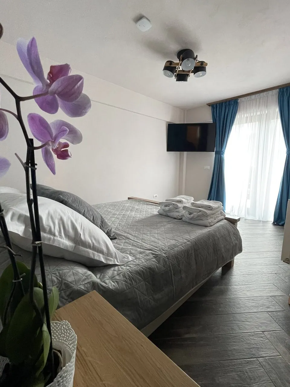 Dormitor cu lenjerie gri și orhidee la fereastră