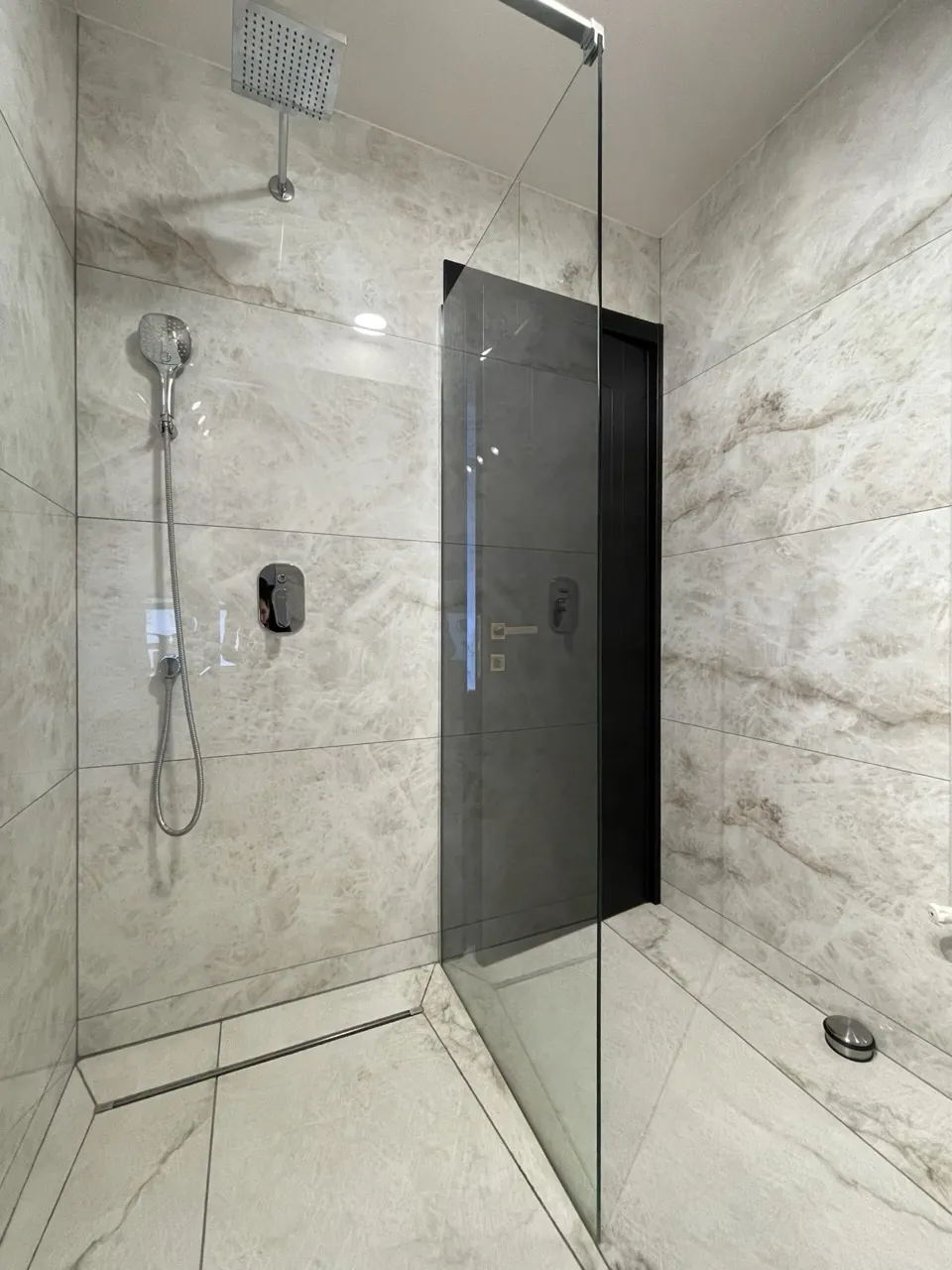Baie modernă cu duș walk-in și finisaje din marmură