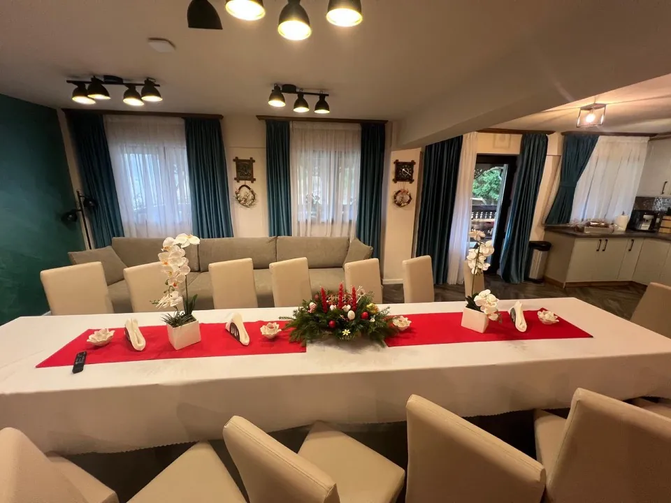 Livingul cu masa mare aranjată și bucătăria deschisă